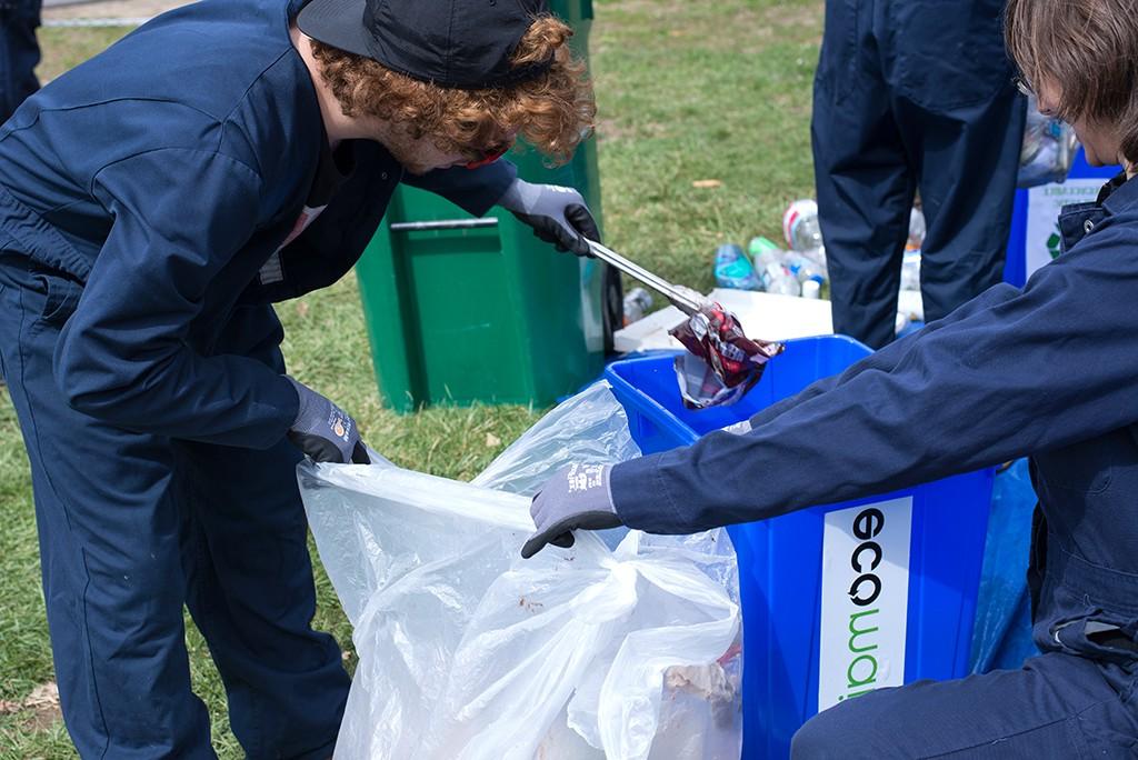 Two students sort through a trash bag to look for items that can be recycled