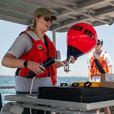 A Marine 科学 student holding a buoy that reads "Fish Rescue"