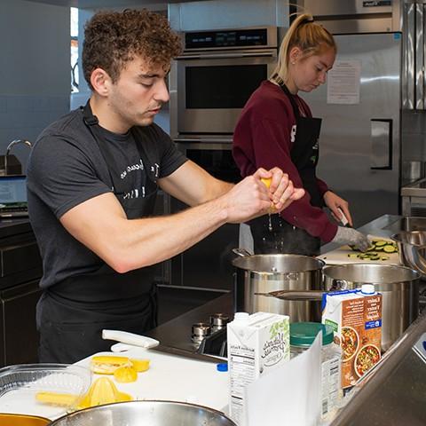 A nutrition student squeezes lemon juice into a pot