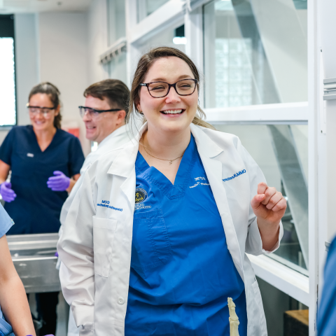 A medical student smiles with her classmates in a UNE lab